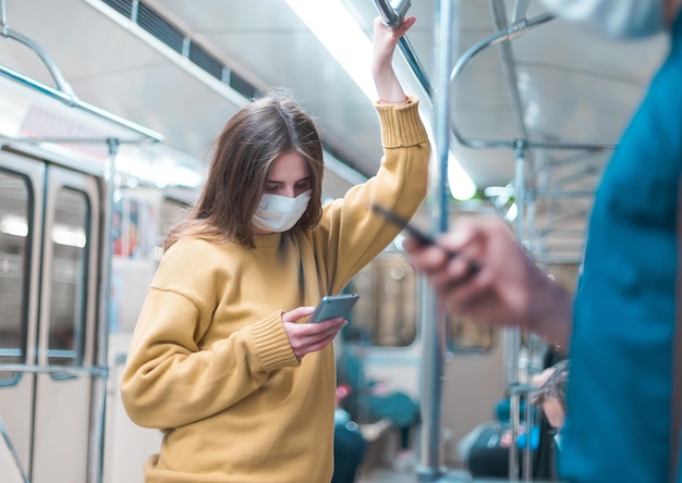 Osoby ze smartfonami stojące w wagonie metra