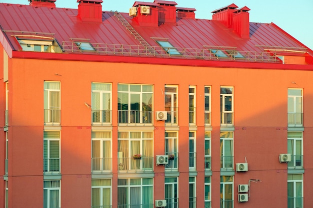 Ostry dach czerwonego nowoczesnego budynku mieszkalnego z wieloma oknami w złotej godzinie