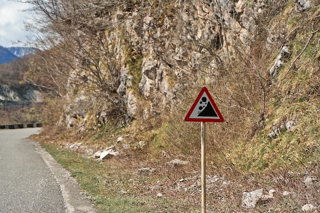 Ostrzegający znak o upadku skały wzdłuż autostrady w górach