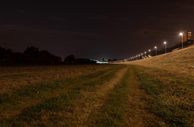 Zdjęcie oświetlona droga pośród pola na tle nocnego nieba