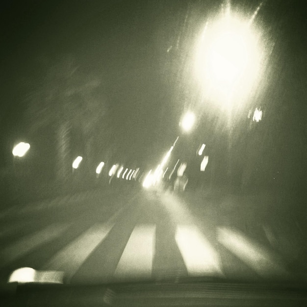 Zdjęcie oświetlona droga w nocy widziana przez przednią szybę samochodu