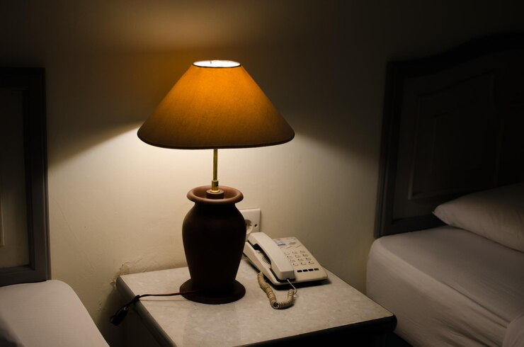 Zdjęcie oświetlona lampa na stole przy ścianie w domu