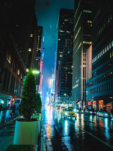 Oświetlona ulica miejska i żółta taksówka w nocy