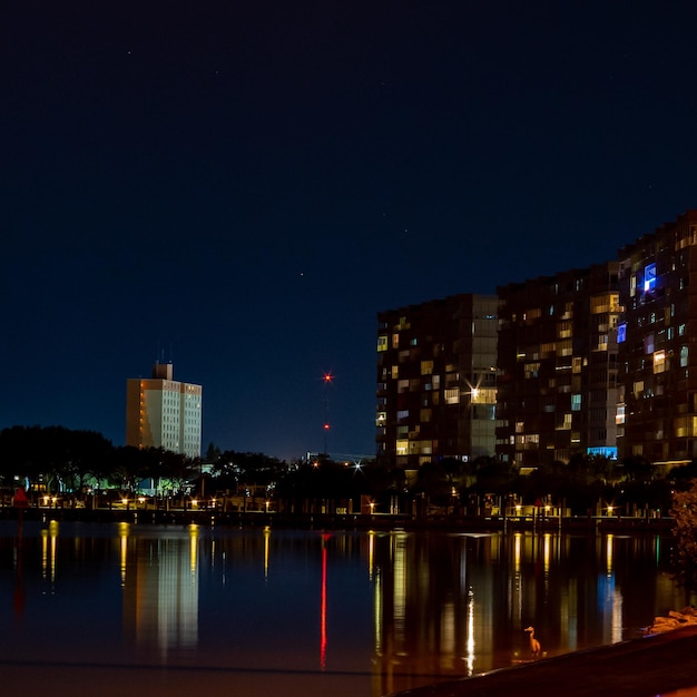 Oświetlone budynki nad rzeką na tle nocnego nieba