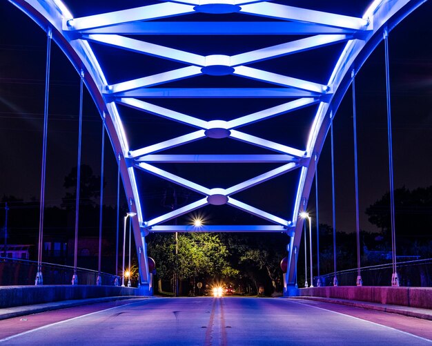 Zdjęcie oświetlone ścieżki światła na drodze na tle niebieskiego nieba w nocy