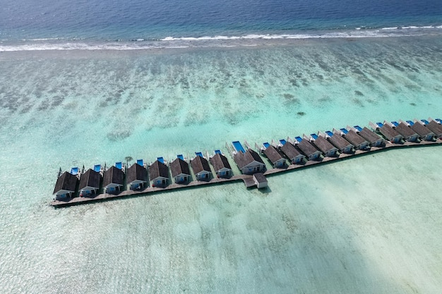 Oszałamiający błękitny ocean i piaszczyste luksusowe hotele na szczycie wody dron widok z lotu ptaka plaża na Malediwach miejsce na tekst