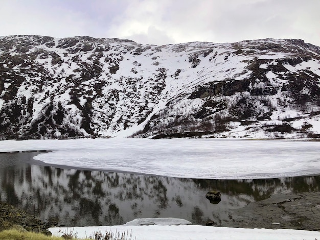 Oszałamiający zimowy krajobraz ośnieżonych gór i górskiego jeziora. Nordycka zima, skandynawska sceneria
