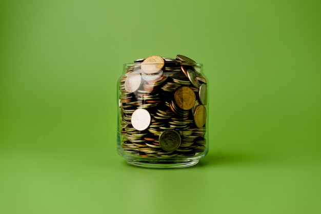 Oszczędności pieniądze zebrane w szklanym słoju na zielonym tle koncepcja oszczędzania pieniędzy