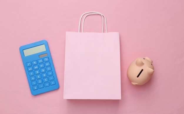 Oszczędzaj pieniądze Koncepcja sprzedaży Torba na zakupy z kalkulatorem Skarbonka na różowym tle Widok z góry