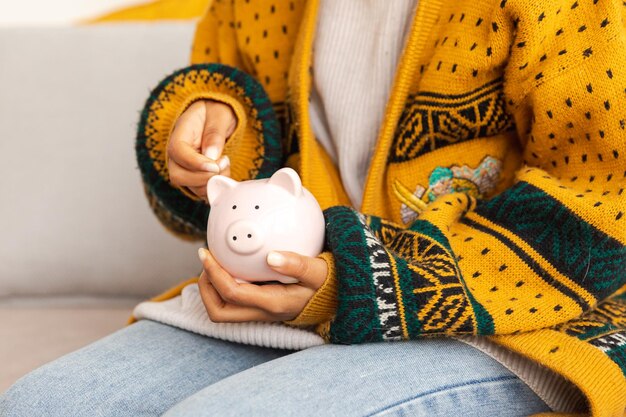 Oszczędzając pieniądze na inwestycje dla przyszłej kobiety ręce trzymające różową skrzynkę i wkładające monety