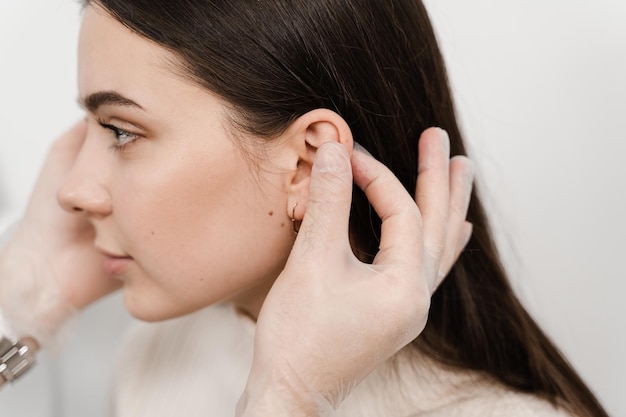 Otoplastyka chirurgii ucha Chirurg bada uszy dziewczynki przed otoplastyką chirurgii plastycznej Otoplastyka chirurgiczna zmiana kształtu małżowiny usznej i ucha