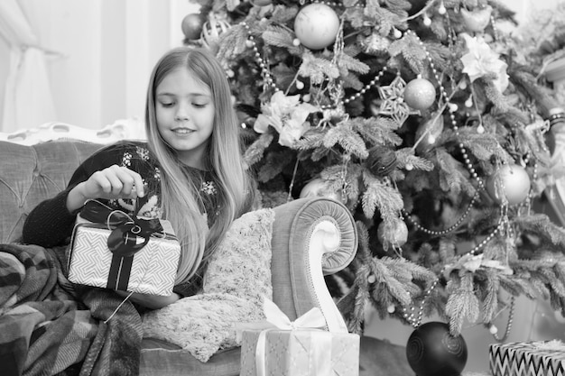 Otwarcie prezentu świątecznegoSzczęśliwego nowego roku Zimowa choinka i prezenty Boże Narodzenie zakupy online Rodzinne wakacje Poranek przed Bożym Narodzeniem Mała dziewczynka Dziecko ciesz się wakacjami