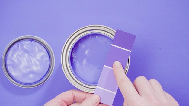 Otwarta metalowa puszka po farbie z fioletową farbą i próbkami farb.