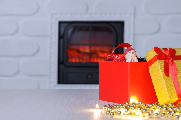 Otwarte pudełko prezentowe na Boże Narodzenie w bałwanku W tle biały ceglany kominek