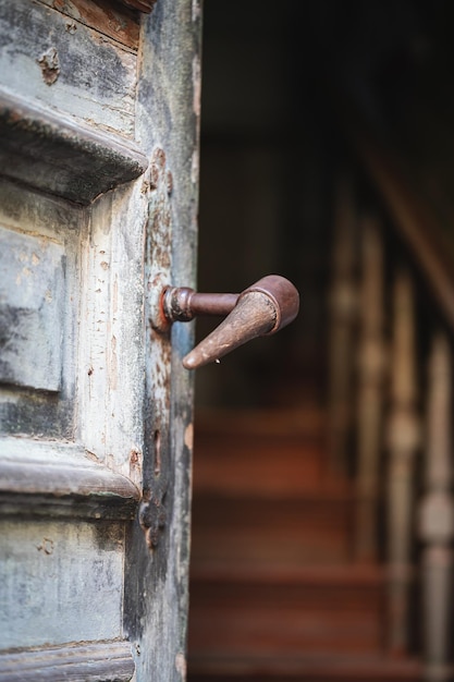 Otwarte stare drewniane drzwi w antycznym niebieskim kolorze z metalową klamką