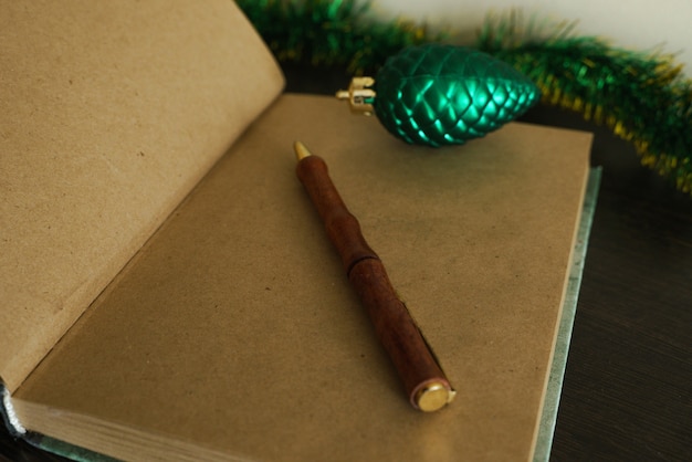 Otwarty czysty notatnik z postarzanymi brązowymi kartkami i brązowym długopisem w formie pnia drzewa