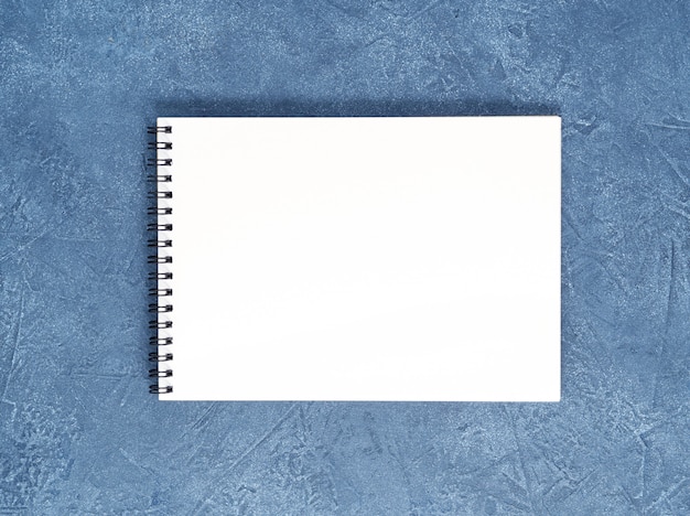 Zdjęcie otwarty notatnik czysta biała strona na wieku granatowy kamienny stół, widok z góry