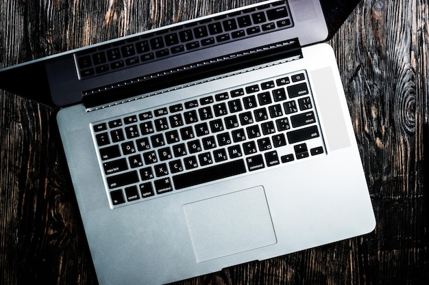 otwarty szary notebook na ciemnym drewnianym stoliku