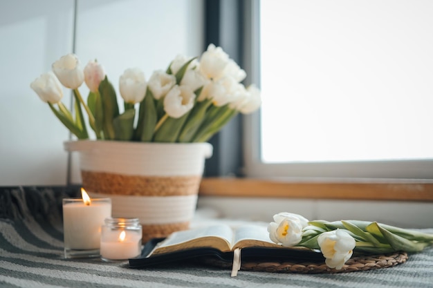 Otwórz Biblię z kwiatami i świecami w przytulnym wnętrzu domu Chrześcijańska piękna poranna fotografia