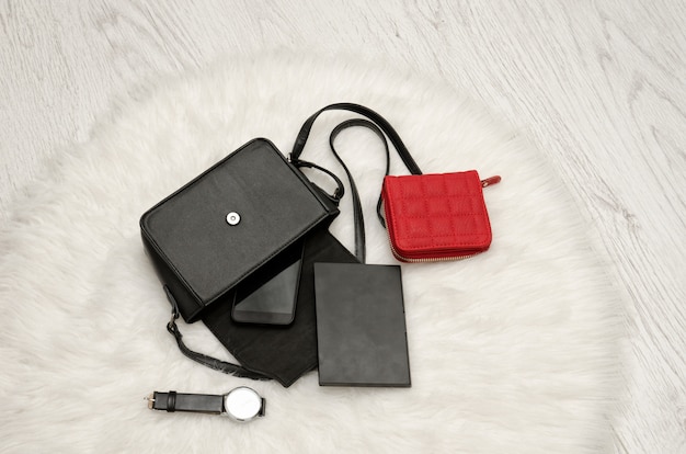 Otwórz czarną torbę z upuszczonymi rzeczami, notatnik, telefon komórkowy, zegarek i czerwoną torebkę.