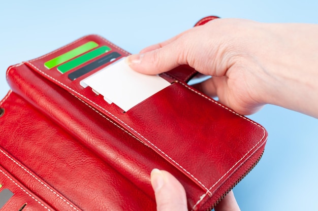 Otwórz czerwoną torebkę i ręce weź kartę Karta kredytowa w portfelu Prosta kompozycja na niebieskim tle Ręce wyjmij kartę z torebki Zapłać pieniądze
