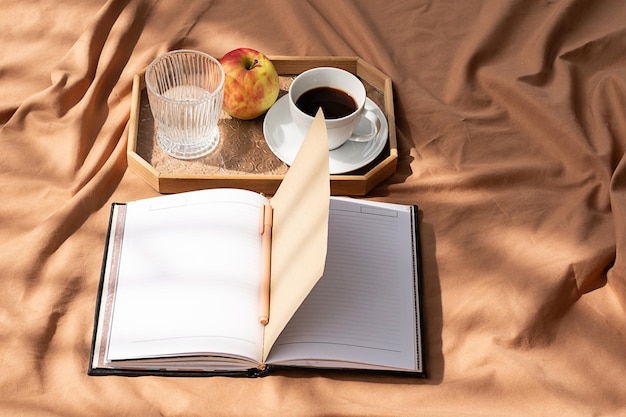 Zdjęcie otwórz notatnik i filiżankę kawy na tacce przyjemny poranek w łóżku