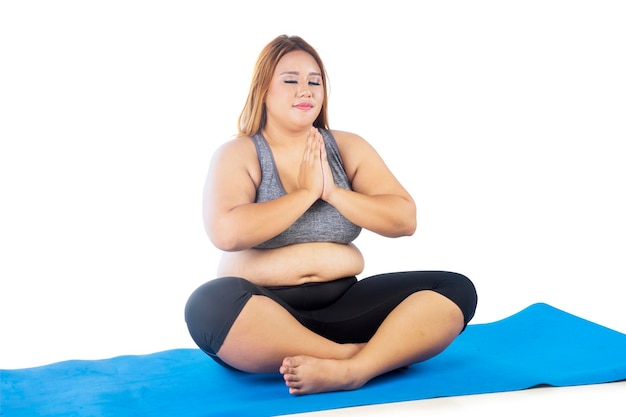 Otyła kobieta ćwicząca jogę siedząc na macie