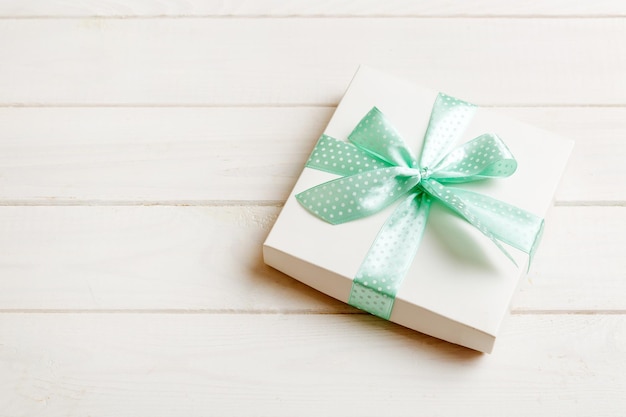 Owinięte Boże Narodzenie lub inne wakacje ręcznie robiony prezent w białym papierze z zieloną wstążką na kolorowym tle Obecna dekoracja pudełka prezent na kolorowym widoku z góry z miejscem na kopię