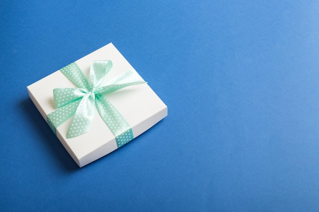 Owinięte Boże Narodzenie lub inne wakacje ręcznie robiony prezent w białym papierze z zieloną wstążką na kolorowym tle Obecna dekoracja pudełka prezent na kolorowym widoku z góry z miejscem na kopię