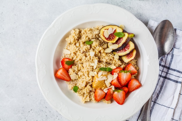 Owsianka Quinoa z truskawkami i figami w białej płytce. Zdrowe śniadanie.