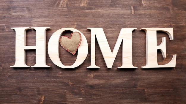 Zdjęcie ozdobne litery tworzące słowo dom z sercem na drewniane tła