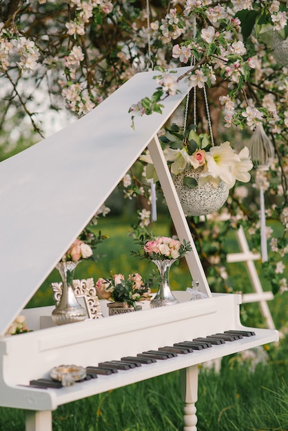 Ozdobny fortepian z wystrojem w kwitnącym sadzie jabłkowym na weselu