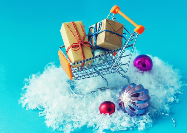 Ozdoby świąteczne i prezenty w wózku na zakupy. Koncepcja Bożego Narodzenia lub Nowego Roku.