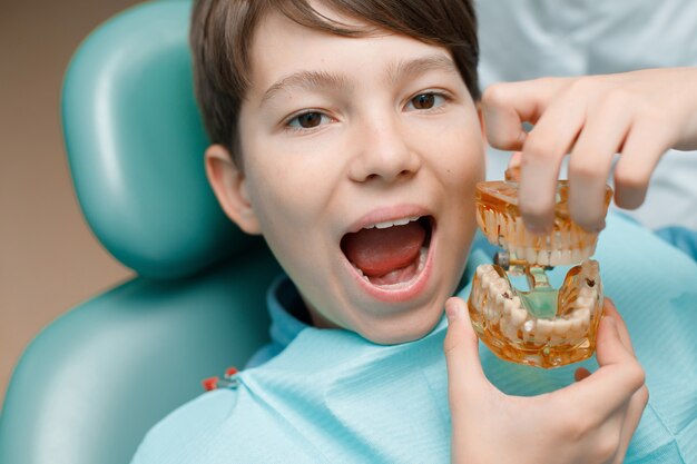 Pacjent na fotelu dentystycznym Nastoletni chłopiec poddawany leczeniu stomatologicznemu w gabinecie dentystycznym