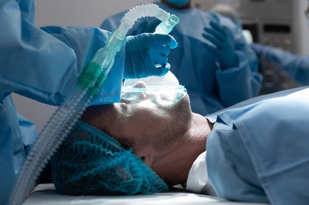 Zdjęcie pacjent rasy kaukaskiej leżący na łóżku chirurgicznym w masce tlenowej na sali operacyjnej