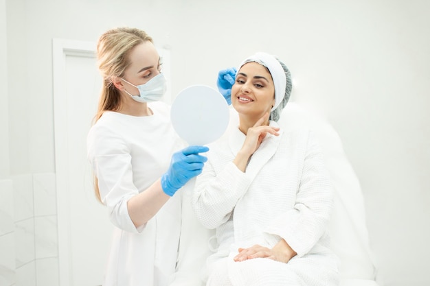 Pacjentka w białym płaszczu siedzi na kanapie w klinice kosmetologii w recepcji u kosmetologa