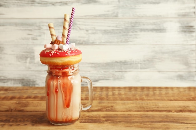 Zdjęcie pączek milkshake i inne słodycze w słoiku na drewnianym stole