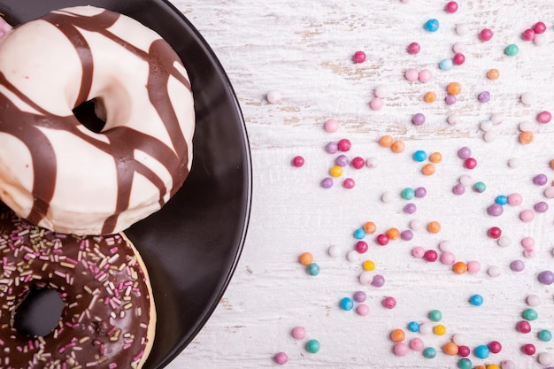 Pączki W Czarnej Płycie I Słodkie Cukierki Na Białym Tle Drewnianych. Pyszne Fast Foody