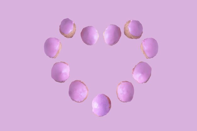 pączki w glazurze cukrowej tworzą serce na różowym tle