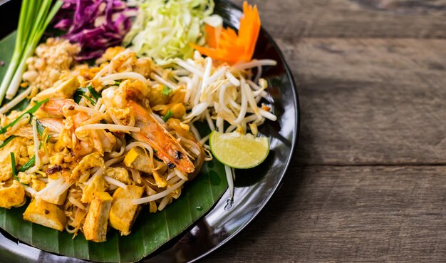 Pad Thai W Czarnym Naczyniu Z Jajkami I Przyprawionymi Krewetkami Na Drewnianym Stole.