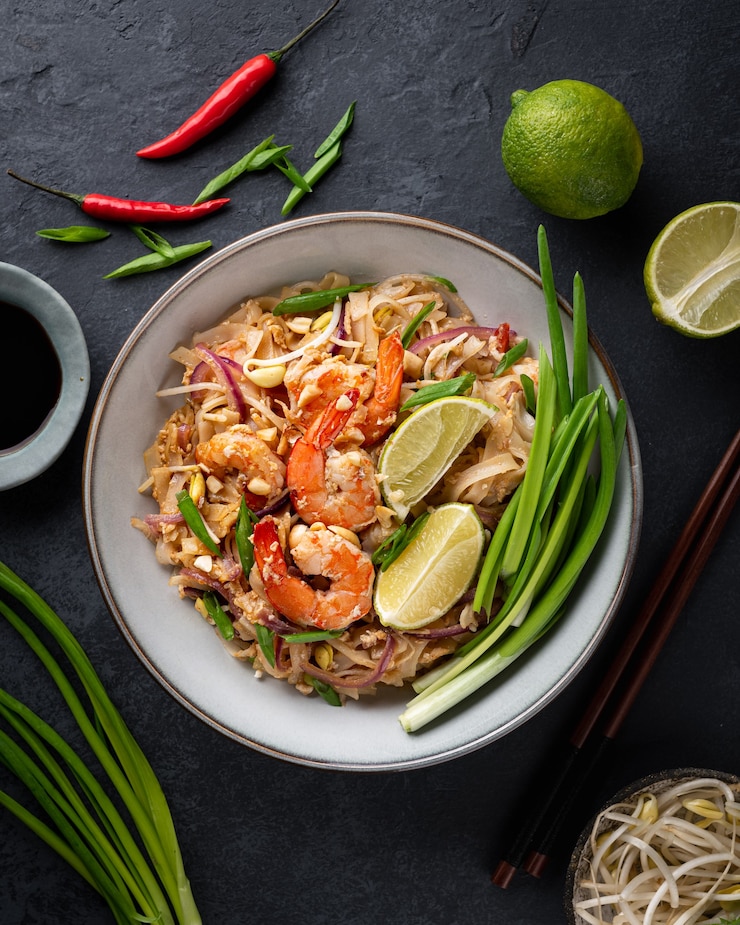 Zdjęcie pad thai z krewetkami na ciemnej kamiennej powierzchni, widok z góry
