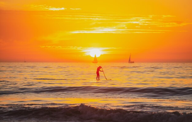 Paddle boarding sea beach z zachód słońca niebo streszczenie tło kopia przestrzeń letnich wakacji i trav