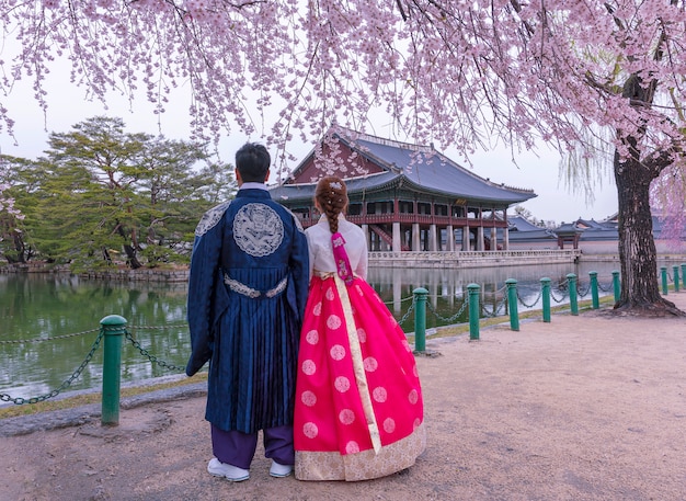 Zdjęcie pałac gyeongbokgung z koreańskim strojem narodowym i wiśniowym kwiatem na wiosnę, seul, korea południowa.