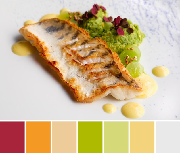 Paleta dopasowywania kolorów z zbliżenia na grillowanym kawałku ryby z zielonym puree i ciemnoczerwonymi jadalnymi roślinami i kiełkami na białawym talerzu
