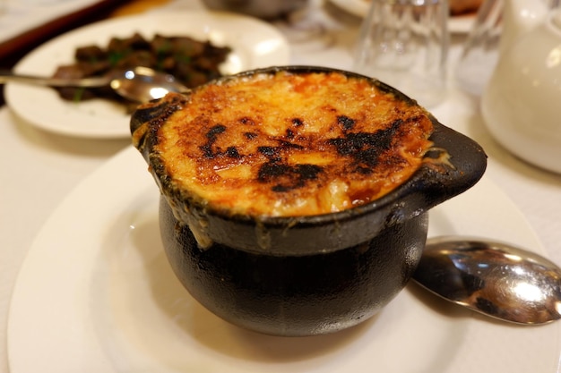 Palona skórka serowa na garnku z tradycyjną francuską zupą cebulową w restauracji w Pau France