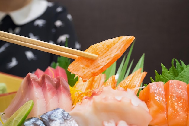 Zdjęcie paluszek krabowy w pałeczkach z japońskim sashimi na talerzu łódki