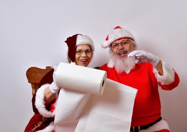 Zdjęcie pan i pani święty mikołaj sprawdzają listę prezentów świątecznych.