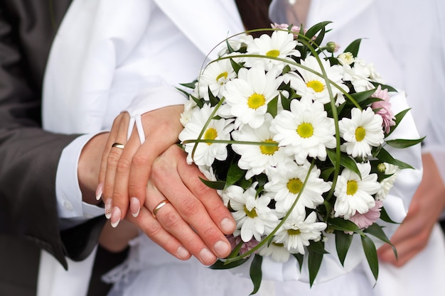 Zdjęcie pan młody obejmuje pannę młodą obrączkami z bukietu ślubnego na rękach nowożeńców para panna młoda położyła ręce na ramionach pana młodego
