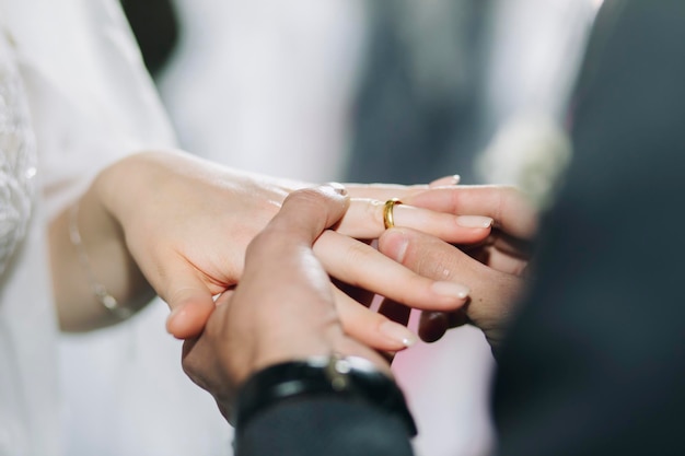 Pan młody umieszcza ślubny złoty pierścionek w kościele podczas ceremonii ślubnej Zbliżenie dłoni młodej pary w kościele