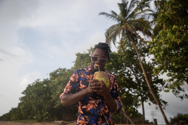 Pan uśmiecha się, delektując się mlekiem kokosowym z kokosa, który trzyma